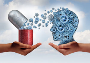 34381764 - brain medicine mental health care concept as hands holding an open pill capsule releasing gears to a human head made of machine cog wheels as a symbol for the pharmaceutical science of neurology and the treatment of psychological illness.